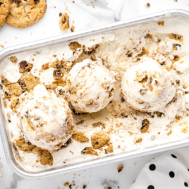 a tin of chocolate chip cookie ice cream, with scoops of ice cream on top of it.