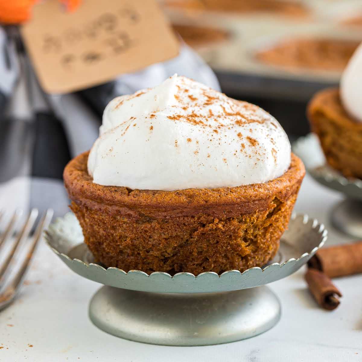 close up shot of pumpkin cupcakes with whipped cream frosting and cinnamon on the top