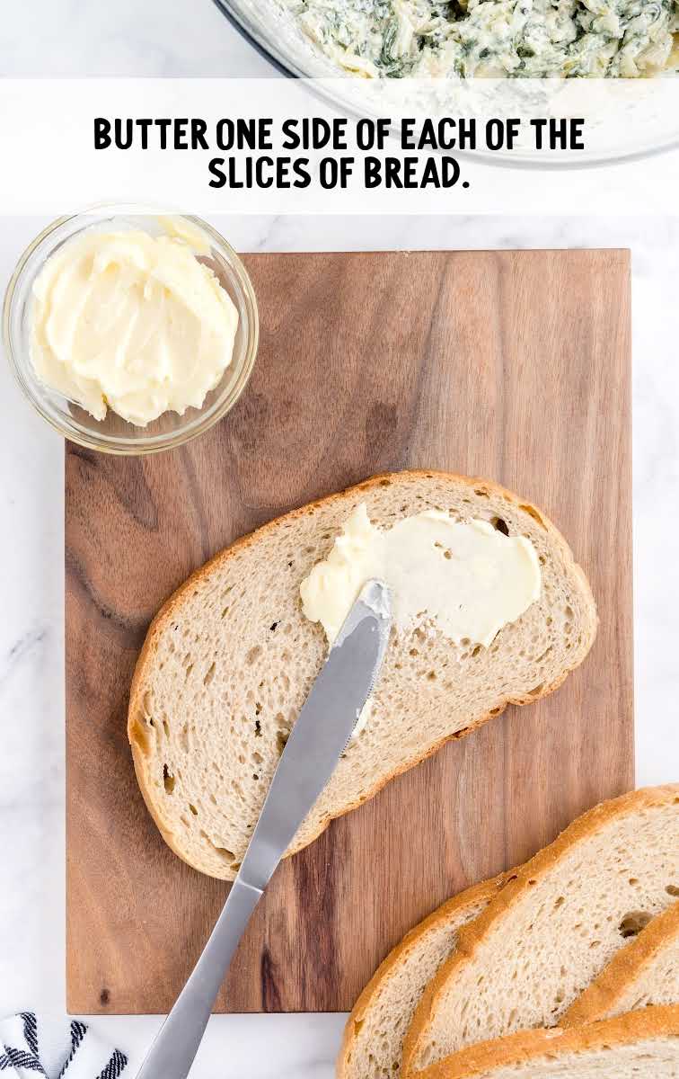 butter being spread on slices of bread on a wooden board