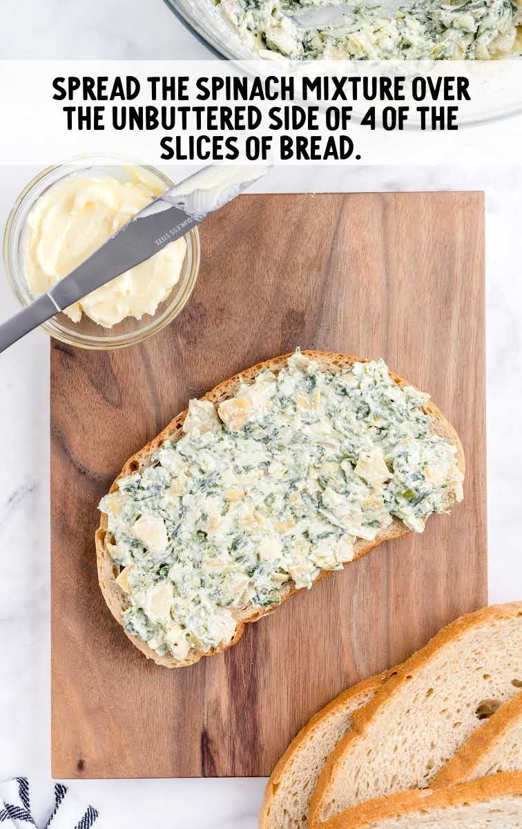 spinach artichoke grilled cheese process shot of spinach mixture spread on slices of bread on a wooden board