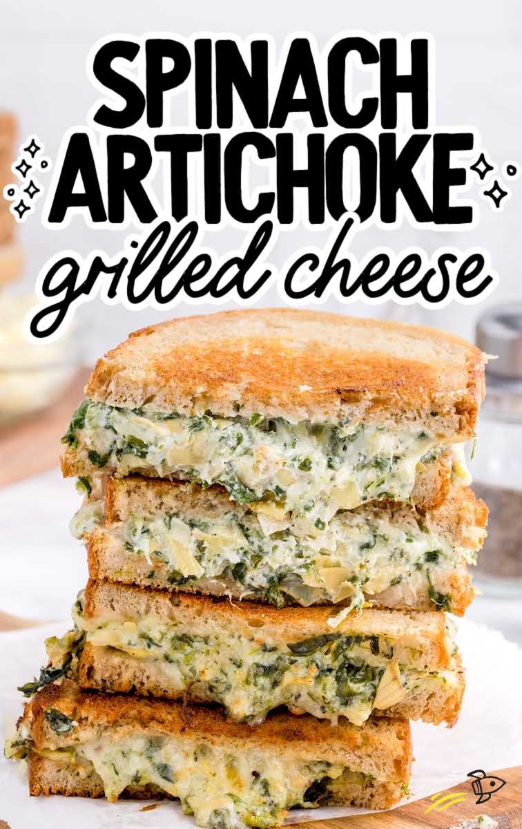 close up shot of slices of spinach artichoke grilled cheese stacked on top of each other on a wooden board
