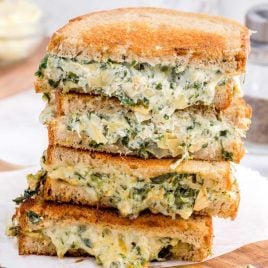 close up shot of slices of spinach artichoke grilled cheese stacked on top of each other