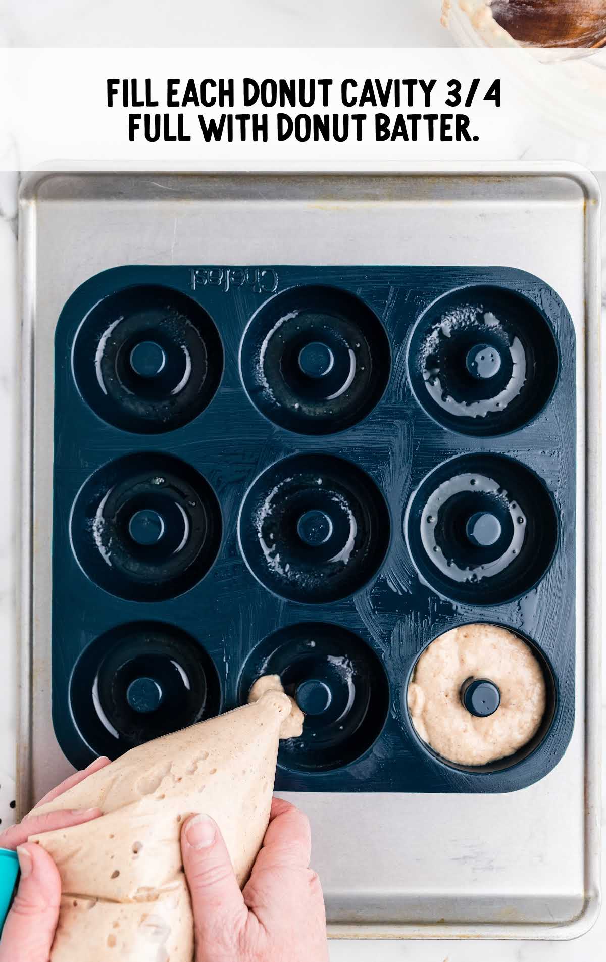 batter being poured into a donut pan