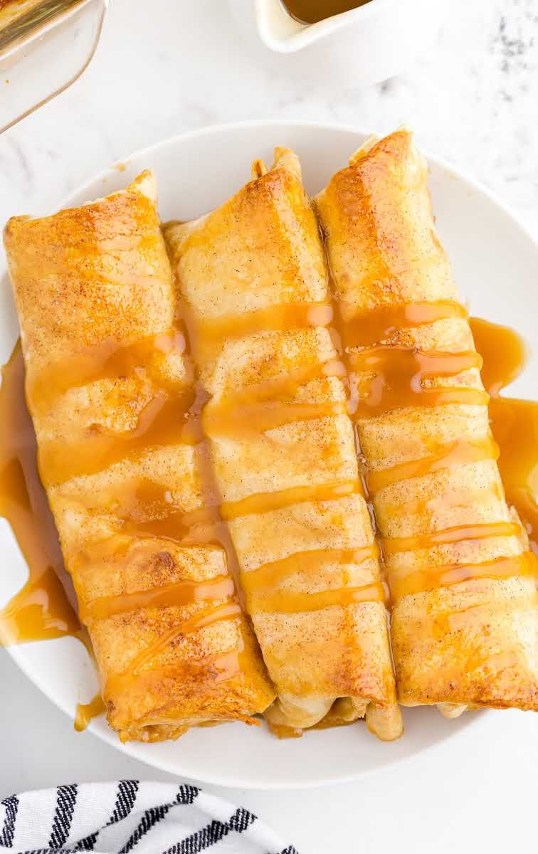 close up overhead shot of Apple Enchiladas drizzled with caramel on a plate