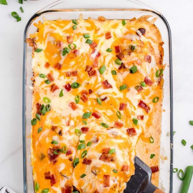close up overhead shot of Baked Crack Chicken garnished with bacon and green onions in a baking dish