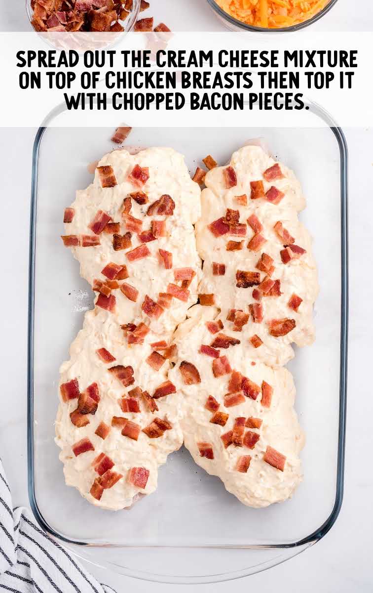 Baked Crack Chicken process shot of chicken breast being topped with cream cheese mixture and bacon pieces