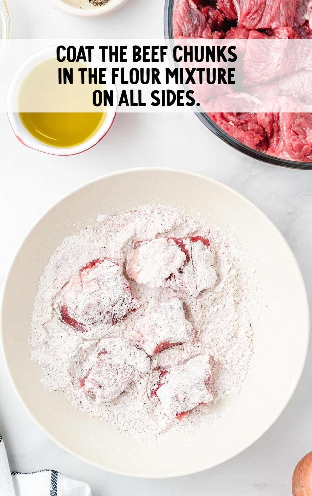 Beef chunks coated in seasoned flour in a bowl, ready to be browned for stew preparation.
