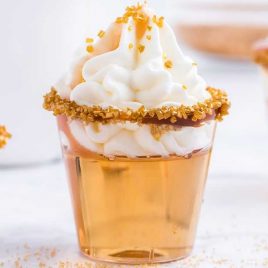 close up shot of Butterbeer Jello Shots topped with whipped cream and caramel topping