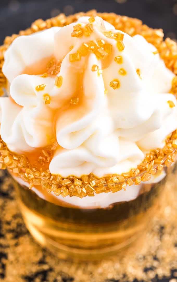 close up shot of Butterbeer Jello Shots topped with whipped cream, caramel topping, and sugar sprinkles