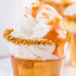 close up shot of Butterbeer Jello Shots topped with whipped cream and caramel topping