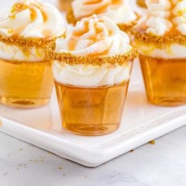 close up shot of Butterbeer Jello Shots topped with whipped cream and caramel topping on a plate