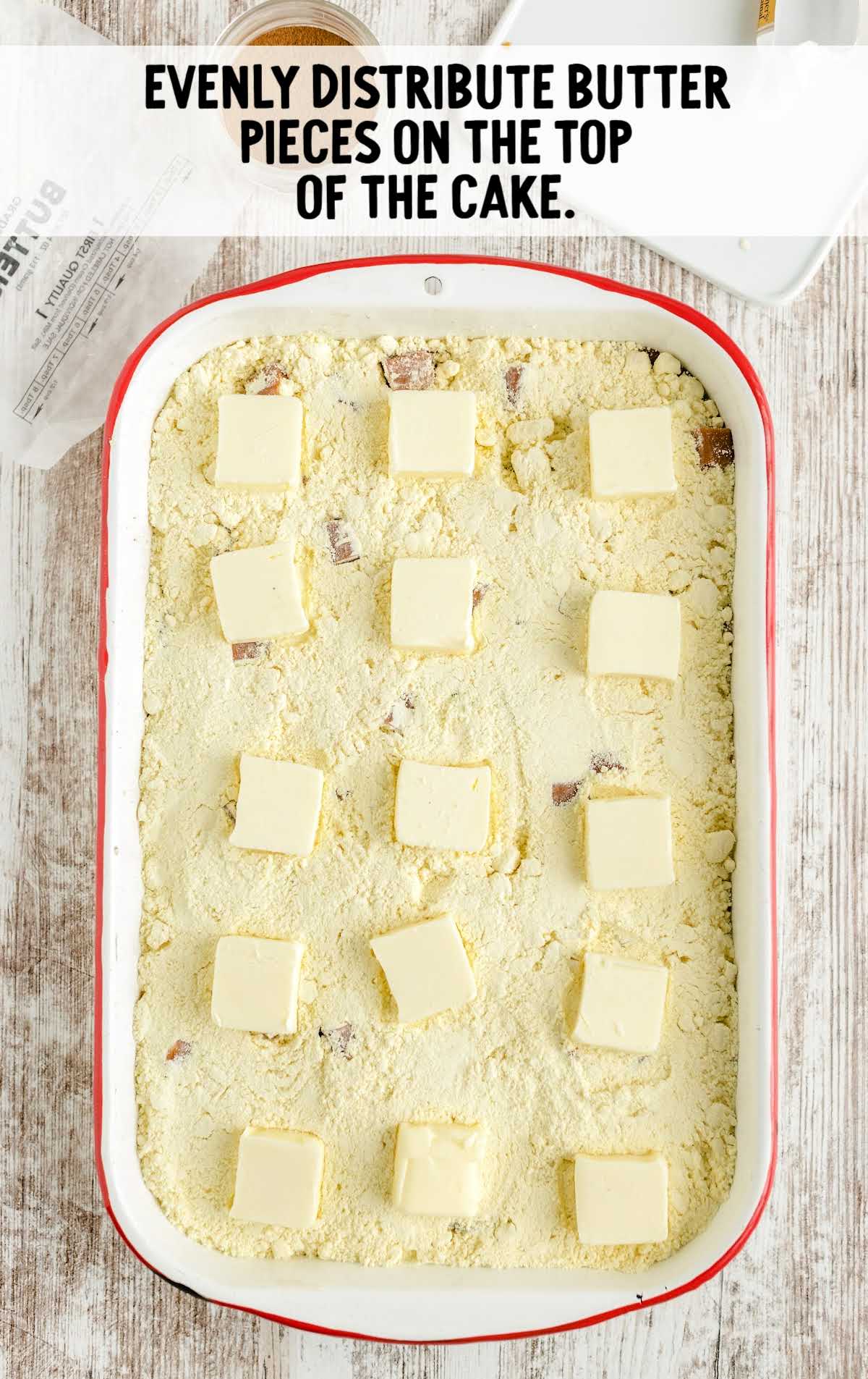 pieces of butter placed on top of cake in a baking dish