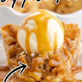 close up shot of a slice of caramel apple pie topped with vanilla ice cream and drizzled with caramel sauce on a plate