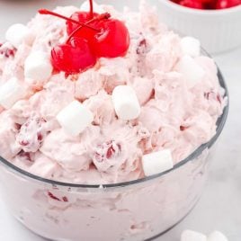 close up shot of Cherry Fluff topped with mini marshmallows and cherries in a large bowl