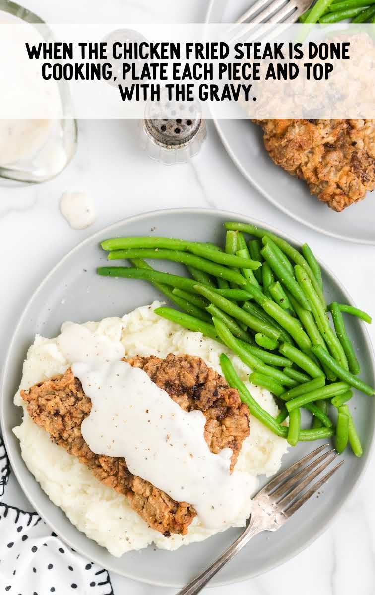 Chicken Fried Steak process shot of steak topped with homemade gravy and served with mashed potatoes and green beans on a plate