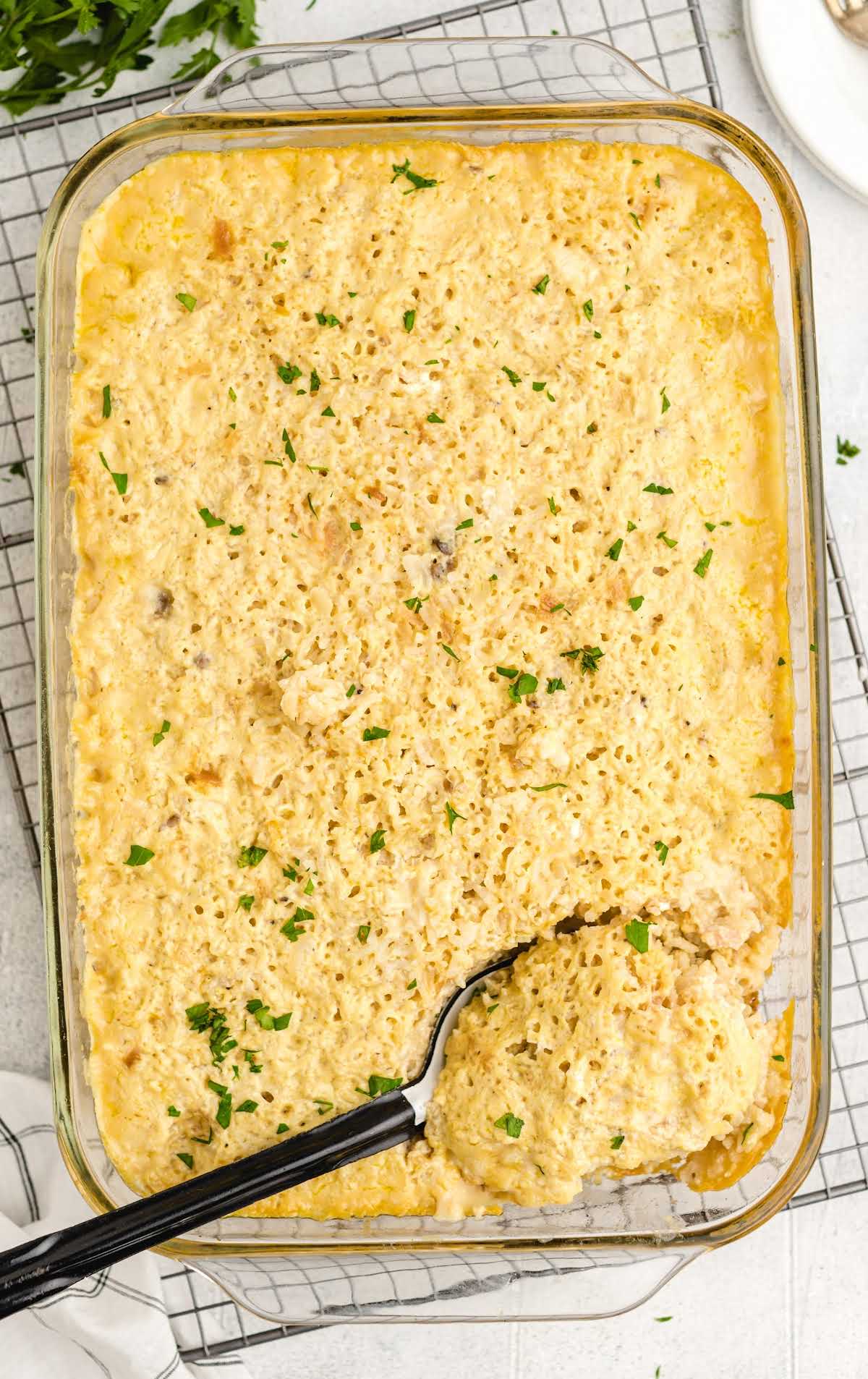 overhead shot of Chicken and Rice Casserole in a casserole dish with a serving being picked up with a large spoon