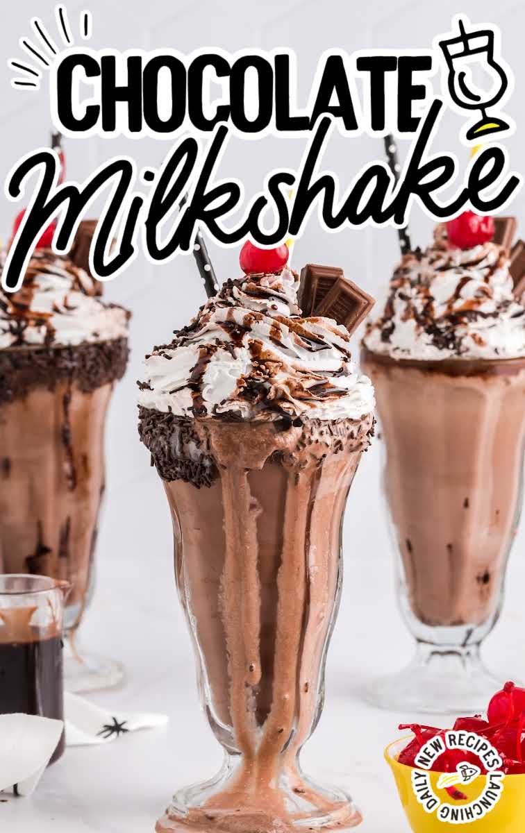 close up shot of a glass of Chocolate Milkshake topped with whipped cream then garnished with Hershey bars, a cherry, chocolate sprinkles, and chocolate syrup