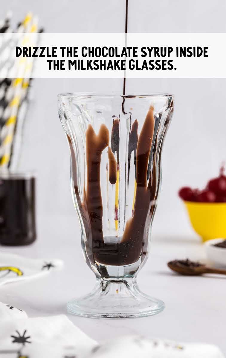 Chocolate Milkshake process shot of chocolate syrup drizzled inside of tall glass
