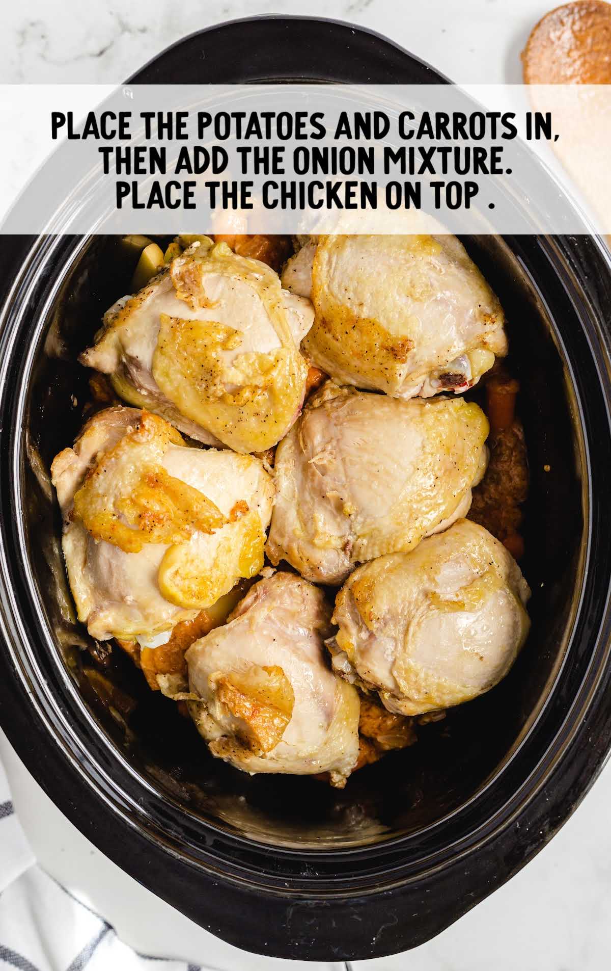 Cooked chicken in the slow cooker being shredded with two forks after several hours.