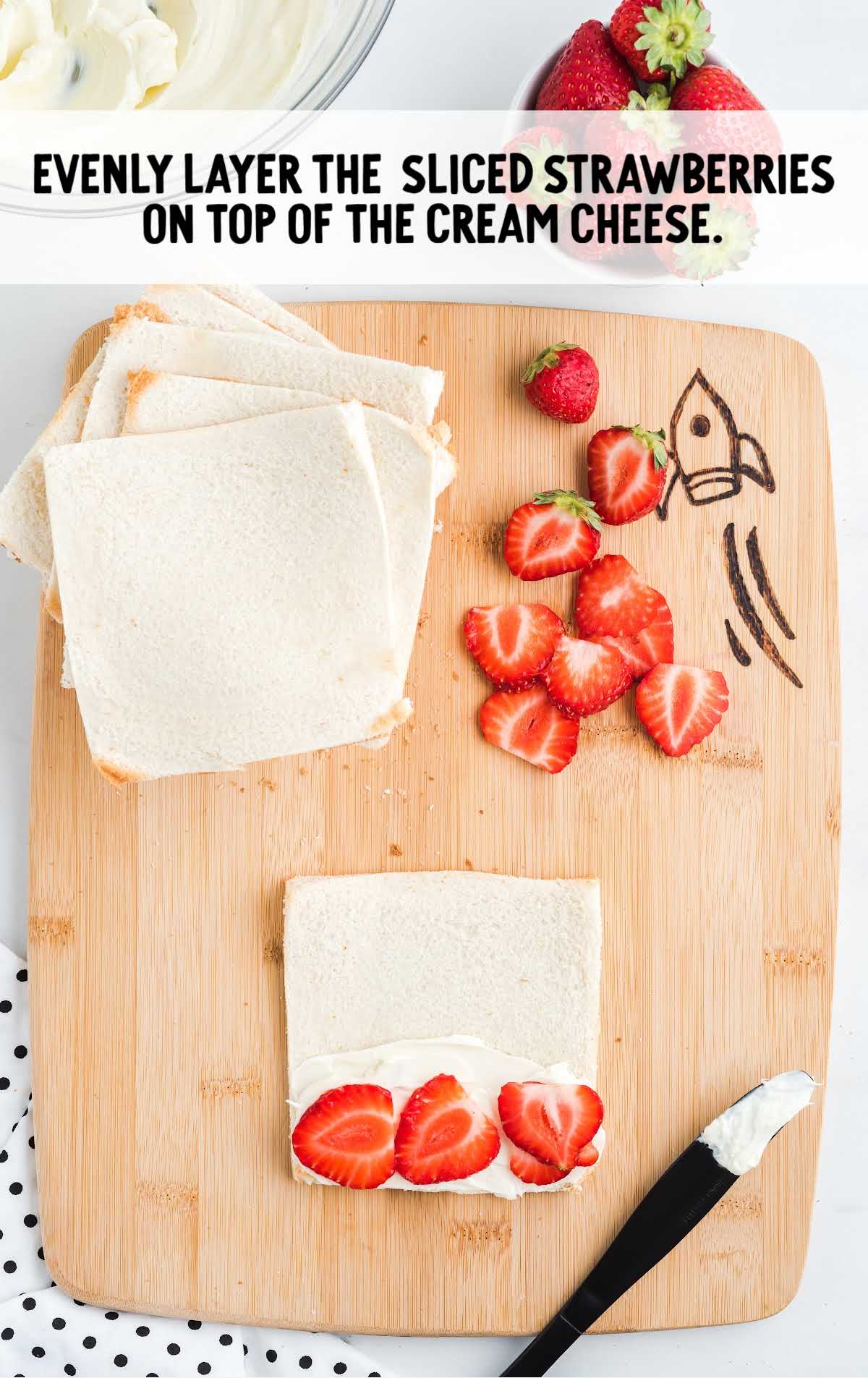 slices of strawberries being layered on top of the cream cheese mixture on the bread