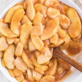 close up overhead shot of a bowl of Fried Apples with a large wooden spoon