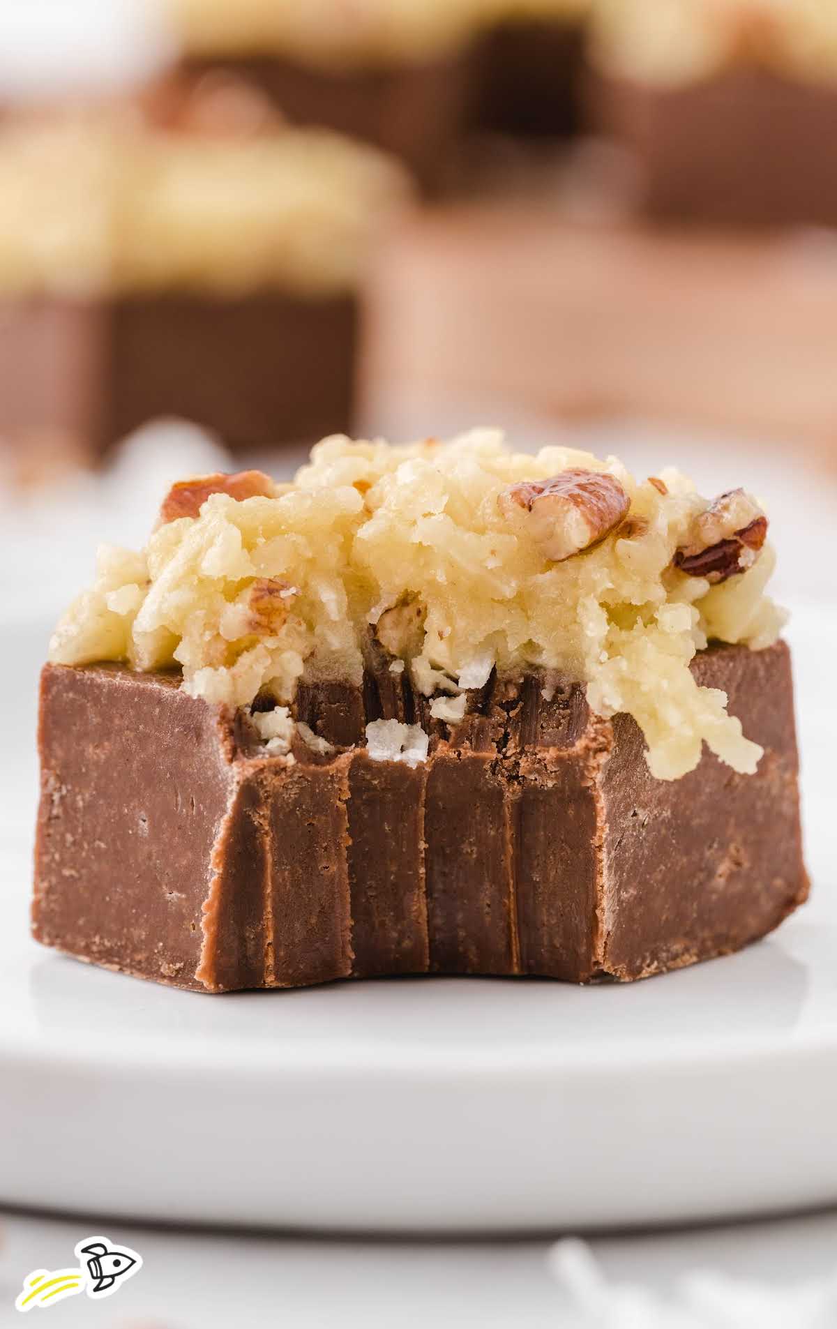 close up shot of German chocolate fudge topped with frosting and a bite taken out of fudge