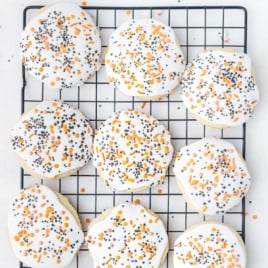 Overhead view of iced Halloween sugar cookies on a cooling rack with orange and black sprinkles