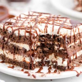 close up shot of icebox cake drizzled with chocolate syrup on a white plate