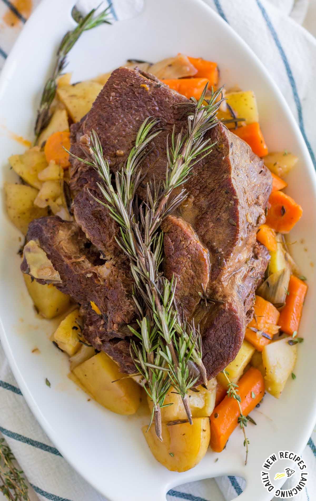 close up overhead shot of instant pot pot roast served over carrots and potatoes on a plate with a piece of thyme on top