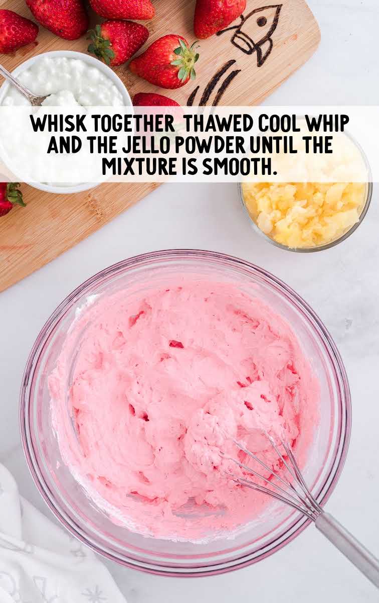 cool whip and jello powder being whisked together in a bowl