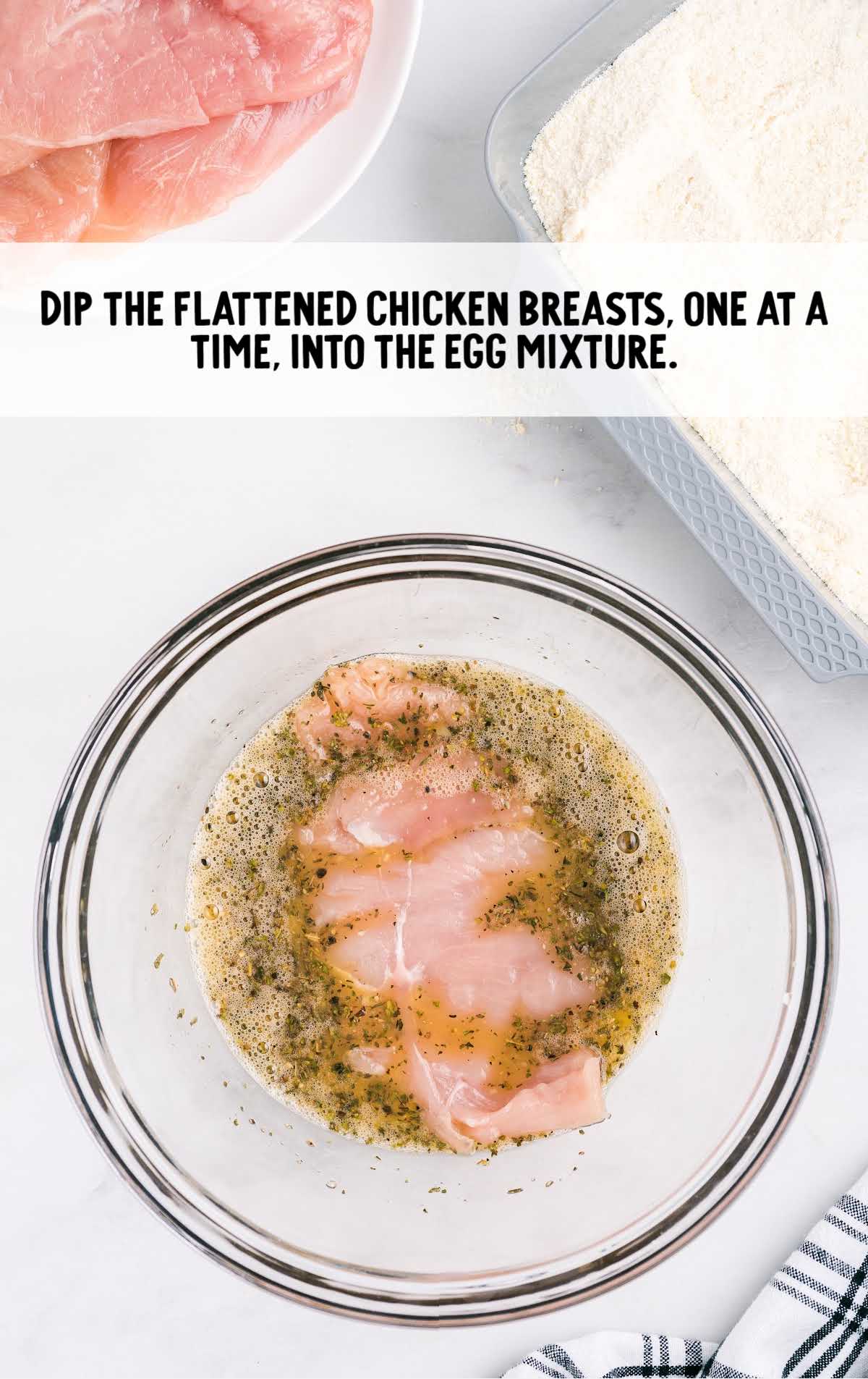 chicken breast dipped into the egg mixture in a bowl
