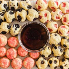 close up overhead shot of strawberry and blueberry Mini Pancakes on a serving tray with a bowl of syrup
