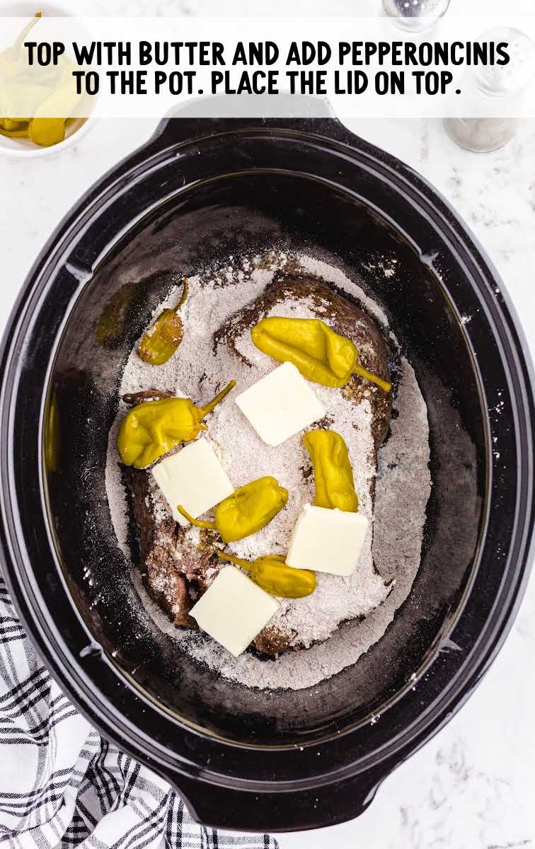 butter slices and pepperoncinis being added to crockpot