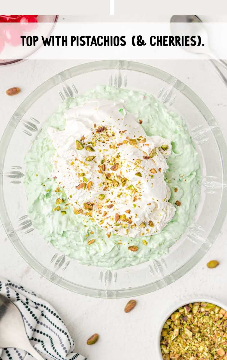 pistachio salad process shot of pistachio salad topped with whipped cream and crushed pisachios