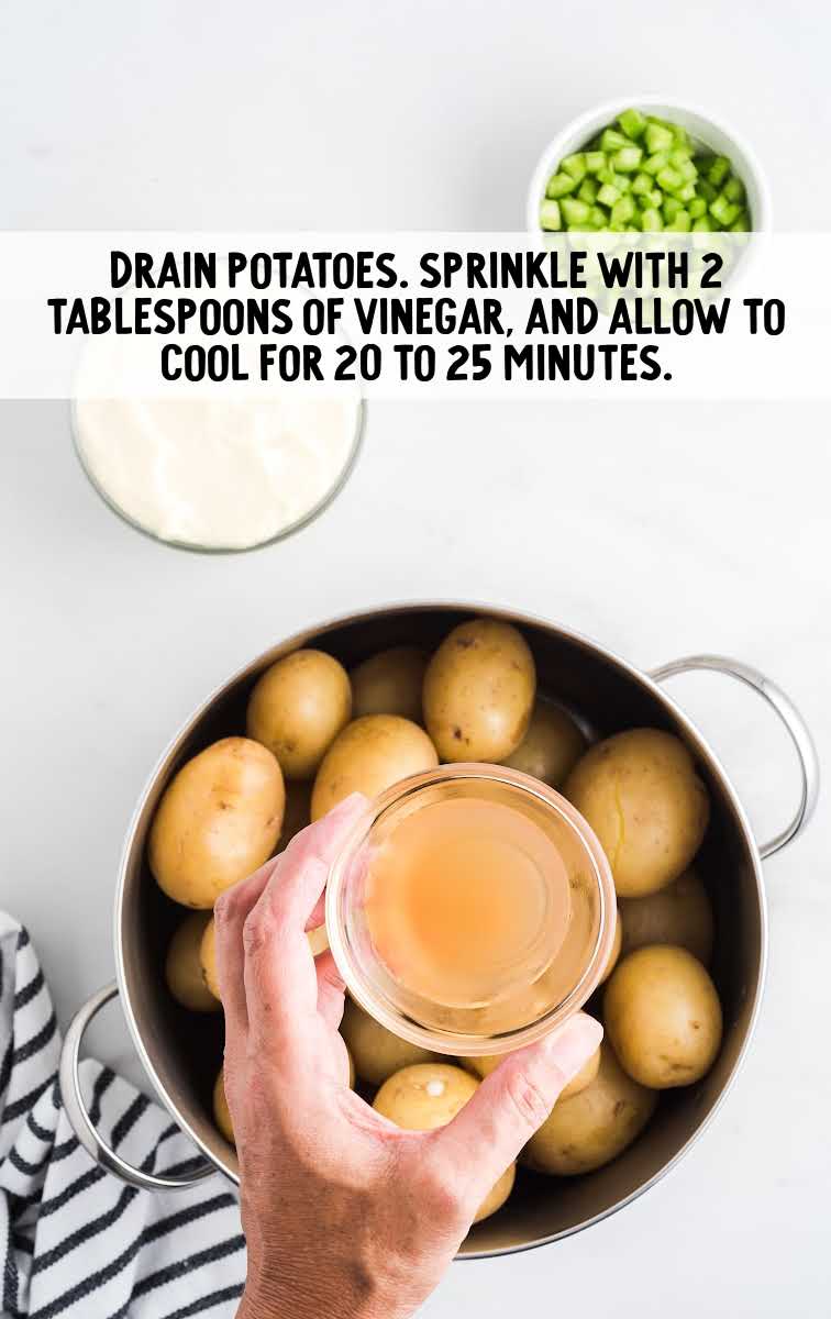 vinegar being held over a pan of potatoes