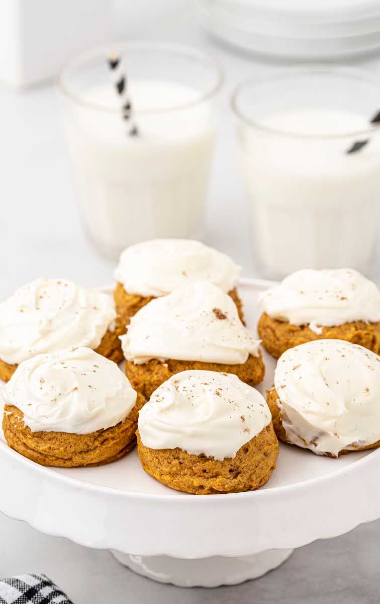 close up shot of Pumpkin Cookies with Cream Cheese Frosting sprinkled with cinnamon on a serving tray