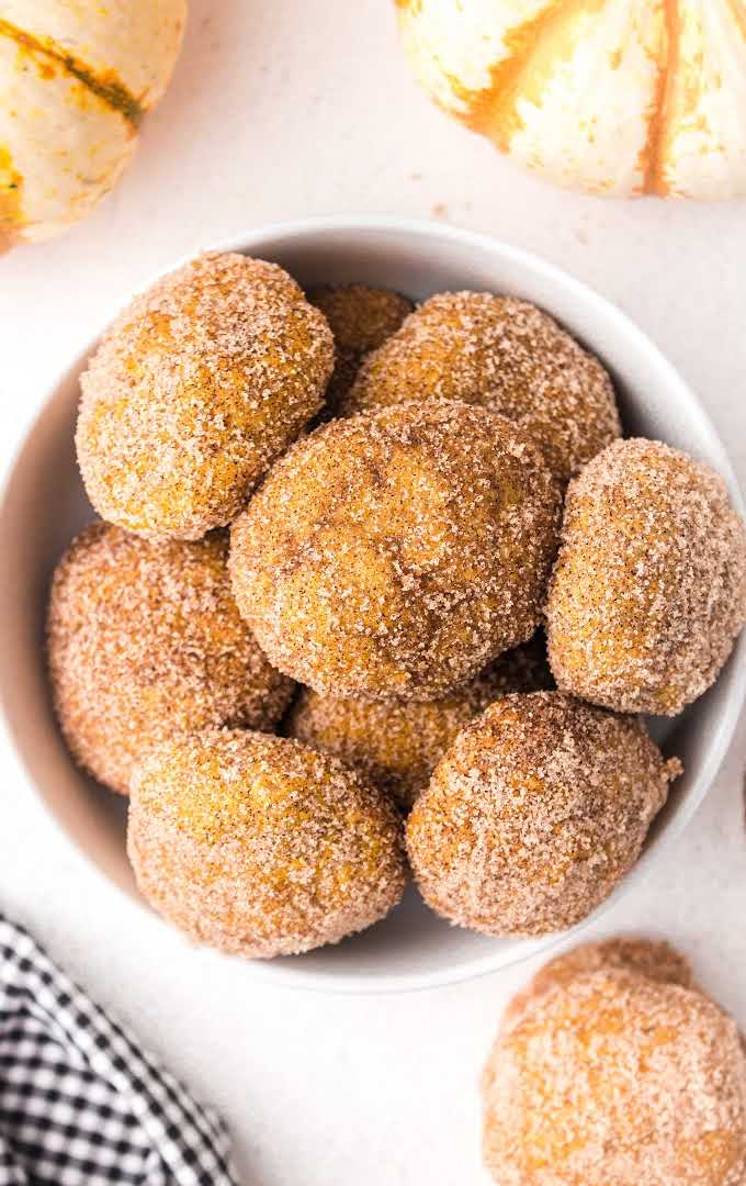 close up overhead shot of a bowl of pumpkin donut holes coated with sugar