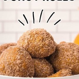 close up shot of a bowl of pumpkin donut holes coated with sugar