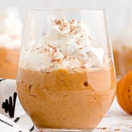 close up shot of a cup of Pumpkin Pudding topped with whipped cream and cinnamon