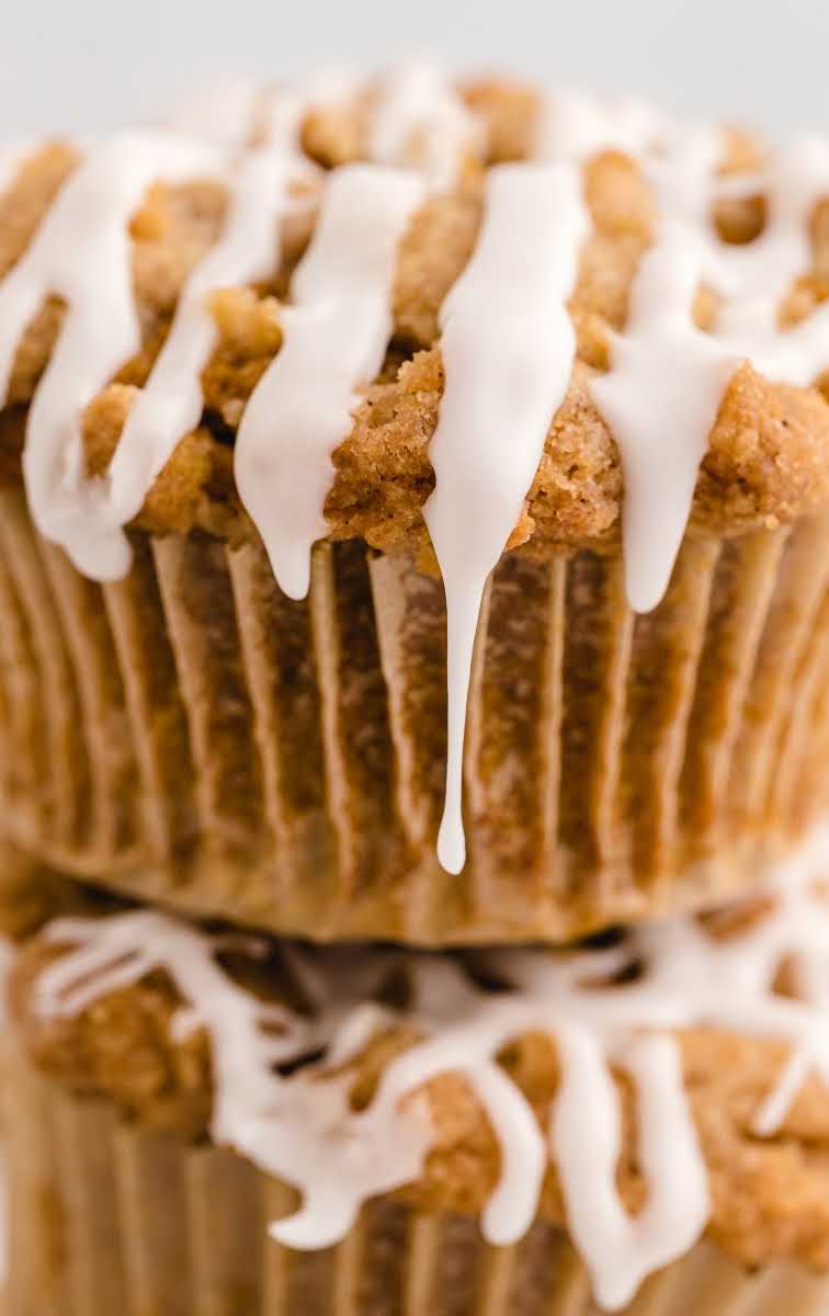 close up shot of Pumpkin Spice Muffins drizzled with icing stacked on top of each other
