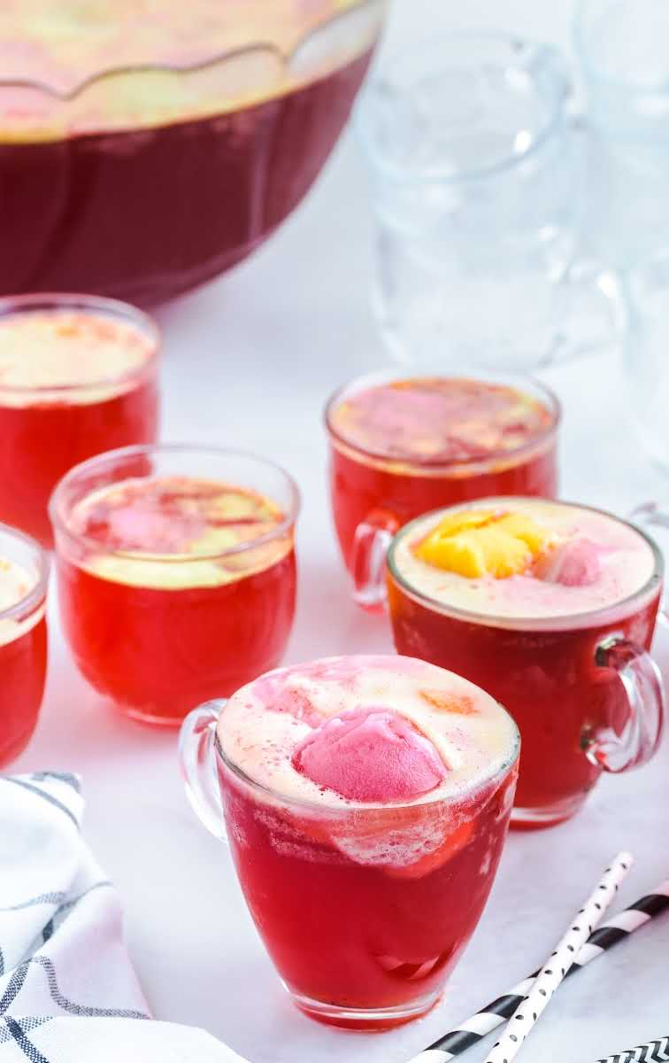 close up shot of glasses of Rainbow Sherbet Punch topped with scoops of rainbow sherbet ice cream