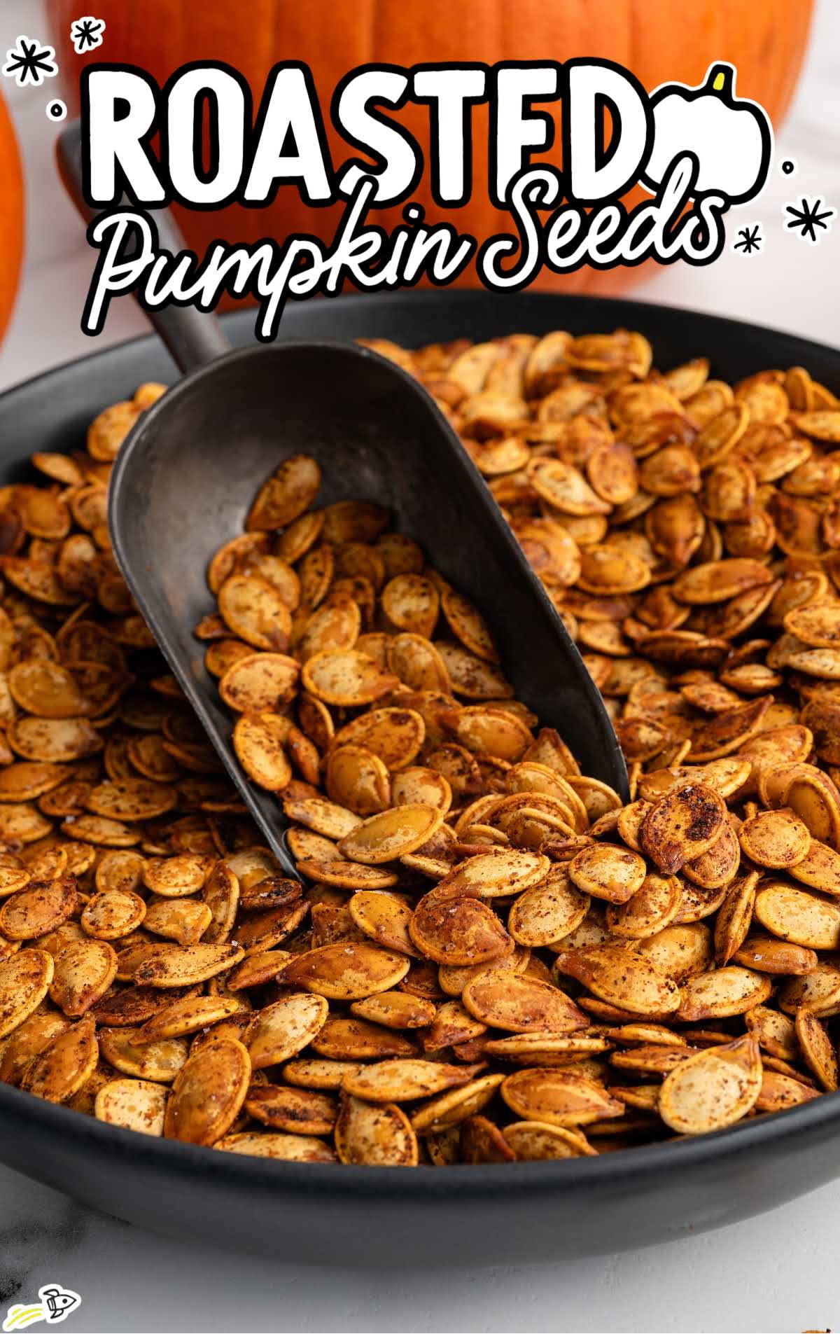 Roasted pumpkin seeds seasoned with spices in a black bowl with a scoop