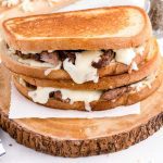 close up shot of Steak Grilled Cheese sandwiches stacked on a wooden board