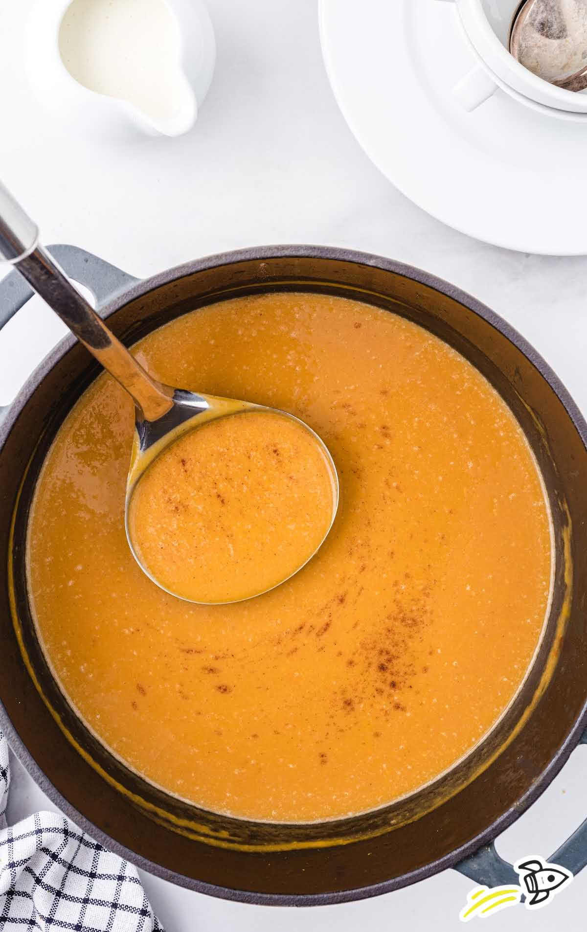 close up overhead shot of butternut squash soup in a pot with a big spoon