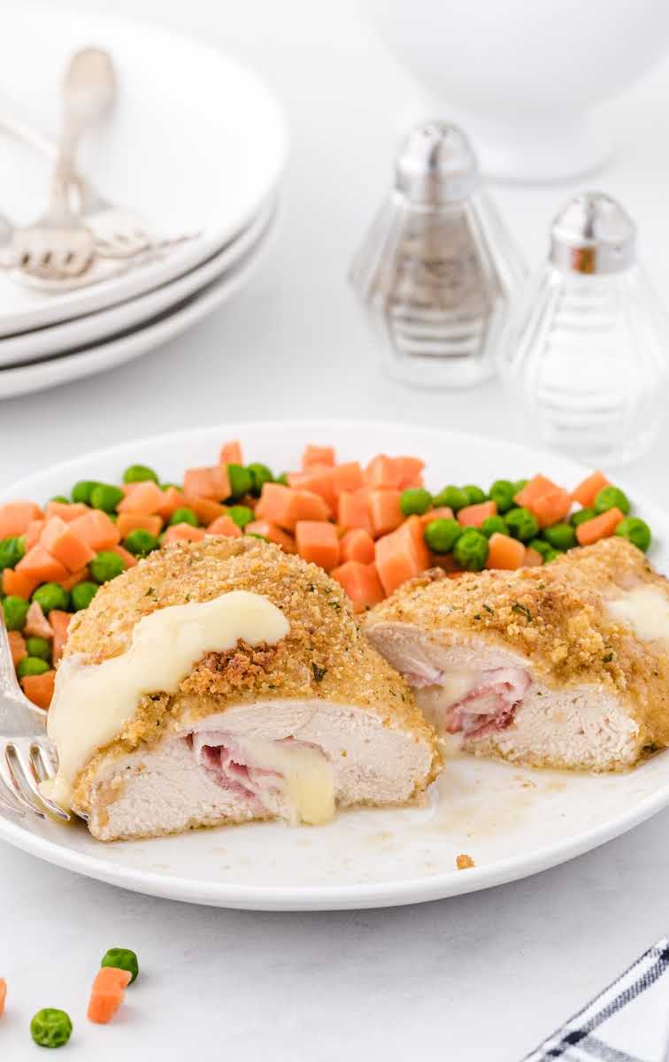 close up shot of pieces of chicken cordon bleu served with vegetables on a plate