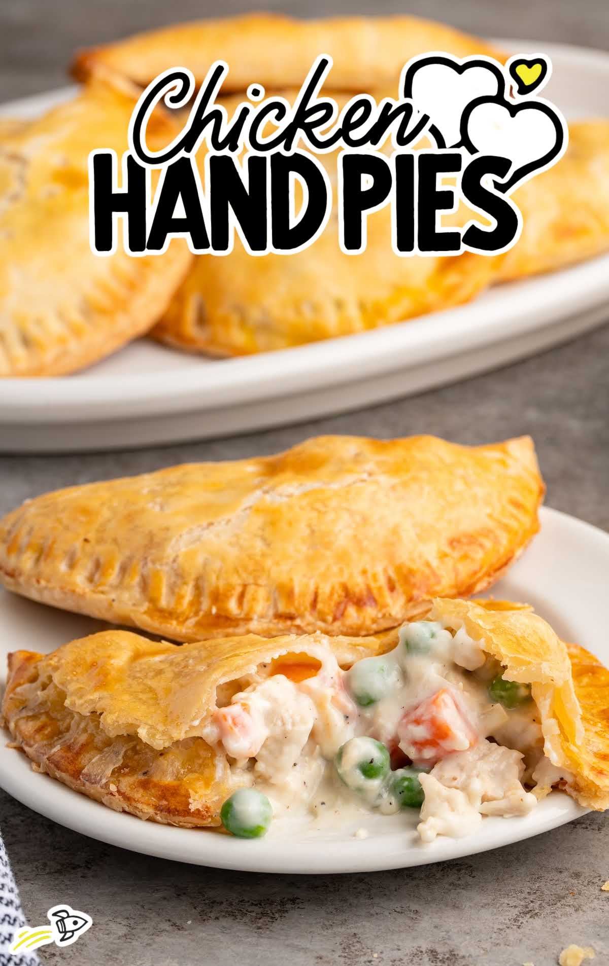 Homemade chicken hand pies on a white plate with one split open to show creamy chicken pot pie filling