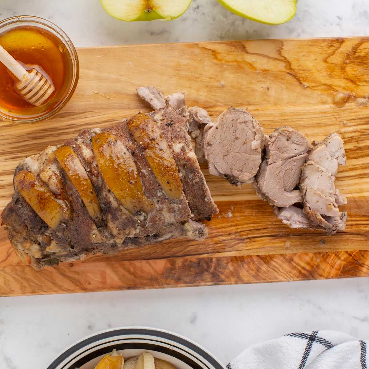 overhead shot of a apple pork tenderloin sliced on a wooden board