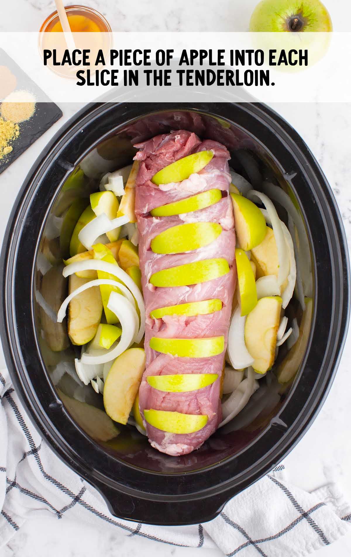 sliced tenderloin stuffed with apple slices placed in the crockpot