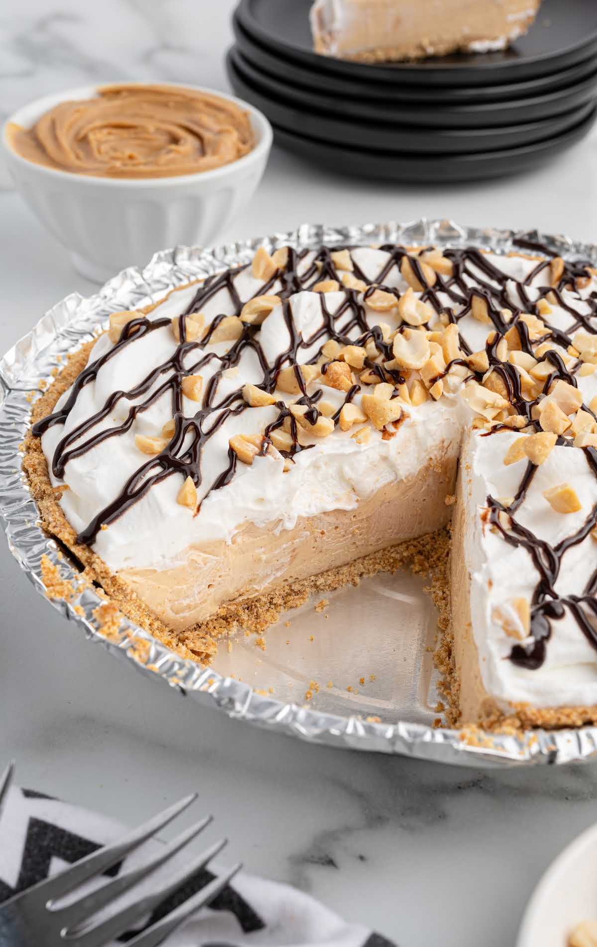Full slice of no bake peanut butter pie on a plate with whipped topping and drizzled peanut butter.