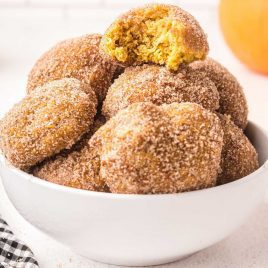 close up shot of a bowl of pumpkin donut holes coated with sugar